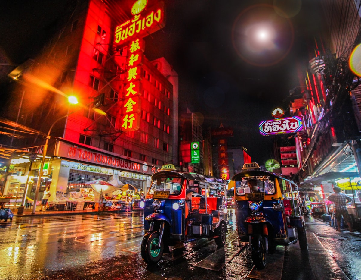 Tuk-tuks on a neon Bangkok street at night
